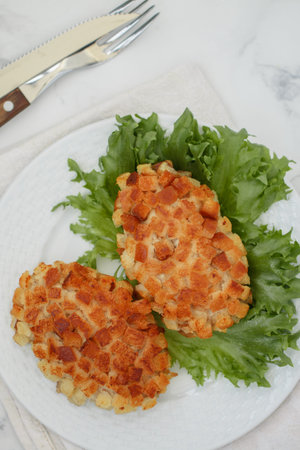 Pozharsky cutlets and lettuce leaf in a white plate on a marble background. selective focus, top viewの写真素材