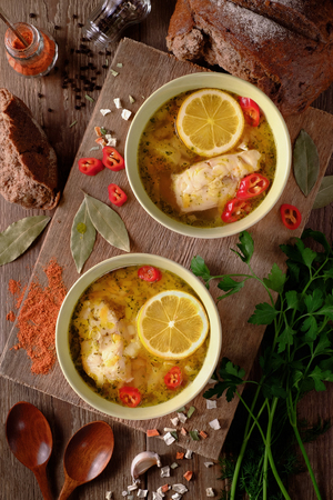 Fish soup with lemon, vegetables and spices on the tableの写真素材