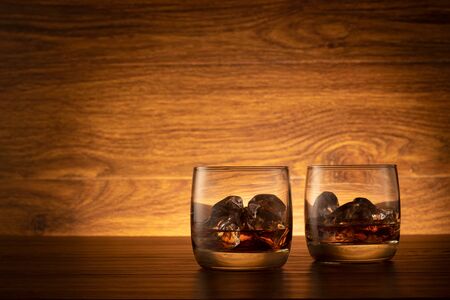 Glass of whisky with ice on a wooden background. Two glasses of whisky on the tableの写真素材