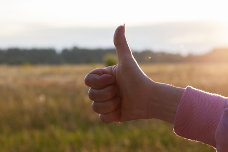 Thumb up at sunsetの写真素材