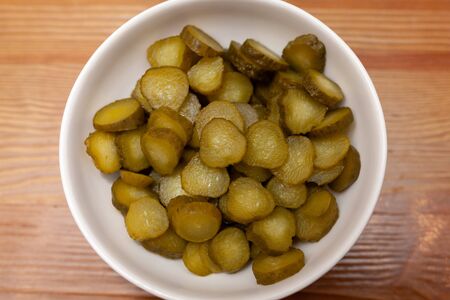 Sliced gherkins cucumbers in a bowl on a wooden tableの写真素材