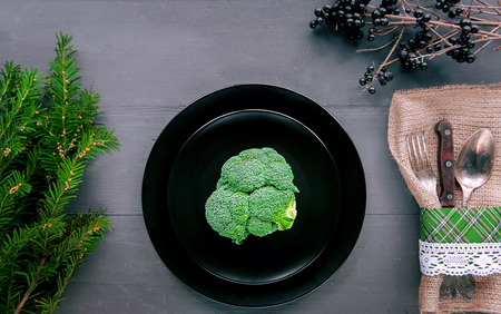 broccoli in a black plate on a wooden table. cutlery. healthy eating conceptの写真素材