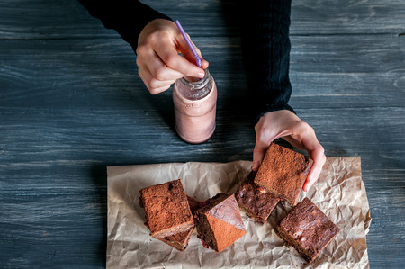 homemade chocolate brownies on dark background. and bottles with hot chocolateの写真素材