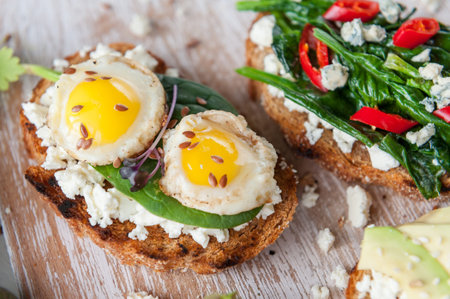 tasty and delicious bruschetta with tomatoes, spinach, feta avocado red chili pepper and blue...