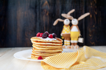 Pancake on a white plate with fruit and powdered sugar on a wooden backgroundの写真素材