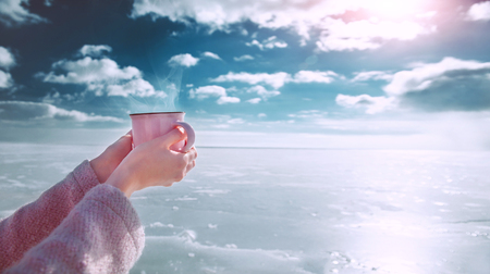 Women's hands with a hot mug on a winter backgroundの写真素材