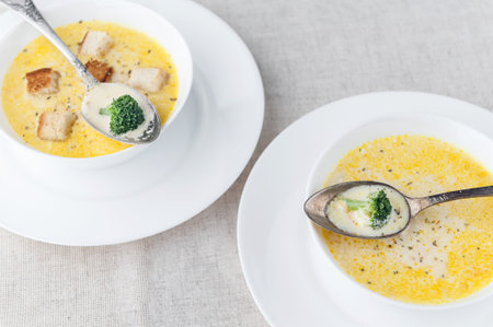 cheese soup with broccoli in a white plate on a white linen tableclothの写真素材