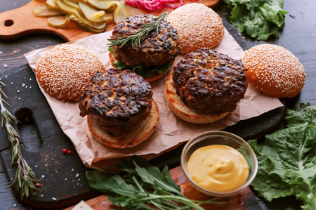 Ingredients for a tasty and juicy burger home in a rustic style with a big chop of beefの写真素材