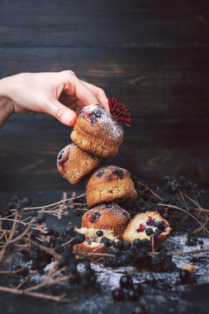 muffin with currants on a dark background. muffins lined tower, one on the other. the bottom...