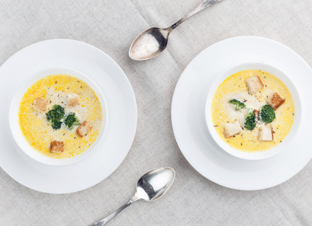 cheese soup with broccoli in a white plate on a white linen tableclothの写真素材