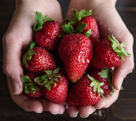 Ripe organic strawberries in hands on a rustic wooden rustic backgroundの写真素材