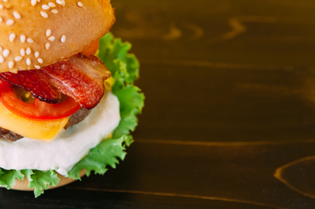 Bright juicy appetizing burgers with chops, cheese, marinated cucumbers, tomatoes and baconの写真素材
