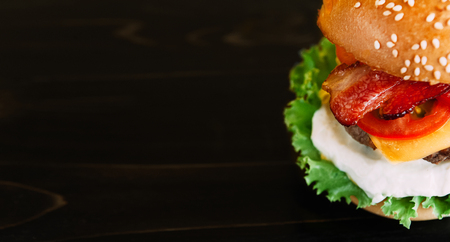 Bright juicy appetizing burgers with chops, cheese, marinated cucumbers, tomatoes and baconの写真素材