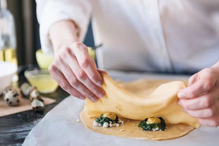 Step by step the chef prepares ravioli with ricotta cheese, yolks quail eggs and spinach with spices. The chef prepares the filling on the doughの写真素材