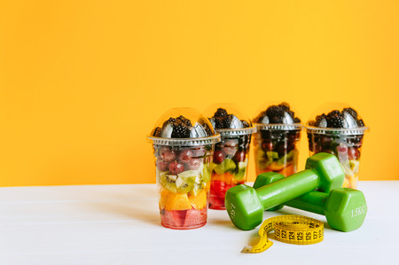 Fruit in a glass, a dumbbell and a tape for measuring the body. Concept of healthy nutrition and weight lossの写真素材