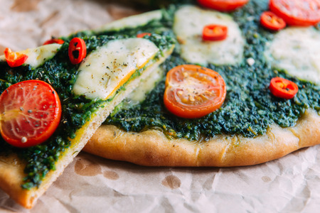 Appetizing pizza with pesto mozzarella and cherry and chili peppersの写真素材