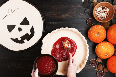 Chef cooks a pie for Halloween with a filling of pumpkin-strawberry jam and peachesの写真素材