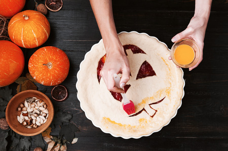 Chef cooks a pie for Halloween with a filling of pumpkin-strawberry jam and peachesの写真素材
