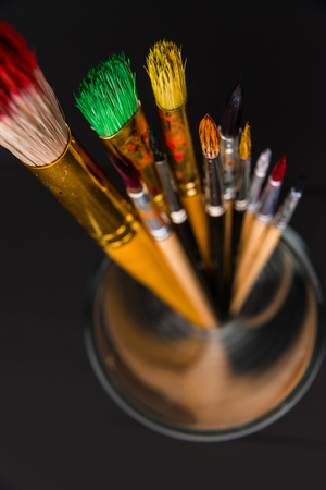 Artistic brushes with traces of paint on a dark background with a shallow depth of fieldの写真素材