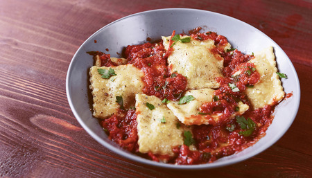 Delicious ravioli with tomato sauce in a plate on a wooden backgroundの写真素材