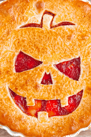 Delicious homemade pie for halloween with a filling of pumpkin-strawberry jam and peachesの写真素材