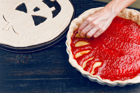 Chef cooks a pie for Halloween with a filling of pumpkin-strawberry jam and peachesの写真素材