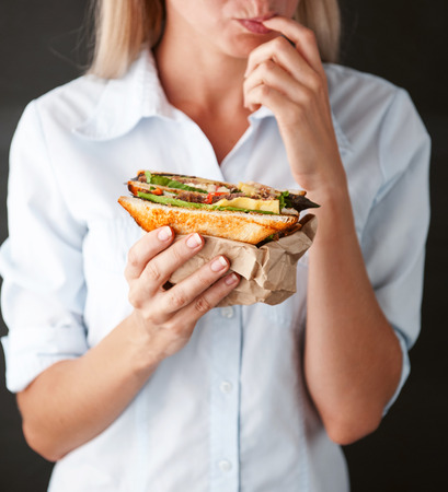 girl licks fingers holding a delicious sandwichの写真素材