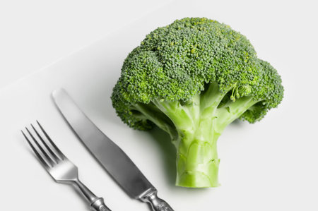 fresh eco-friendly broccoli against white background with fork and knife
