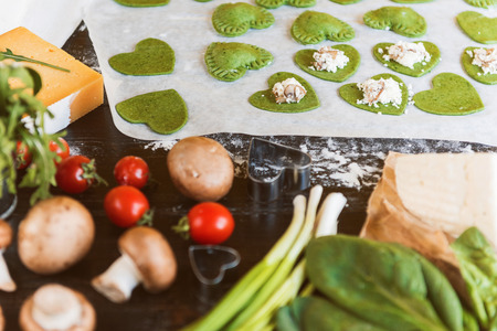 Chef cook step by step makes green ravioli in the shape of a heart for a festive dinnerの写真素材
