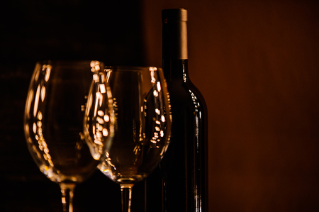 bottles with red wine and wine glasses on a wooden surfaceの写真素材
