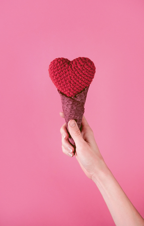 rag heart in a waffle cup in a hand on a pink backgroundの写真素材