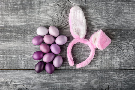 Easter eggs in a fashionable coloring on a gray wooden background with a female hoop with Easter...