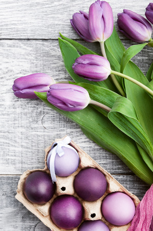 luxurious fresh fashionable purple tulips on a wooden background next to Easter eggsの写真素材