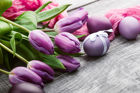 luxurious fresh fashionable purple tulips on a wooden background next to Easter eggsの写真素材