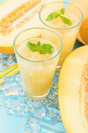 sweet and cold juice from melon in glasses against the background of melon slicedの写真素材