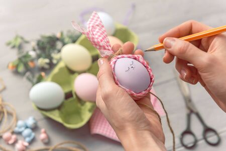 woman makes cute decorative eggs for easter holiday. do-it-yourself easter gifts concept. cute pastel colored eggsの写真素材