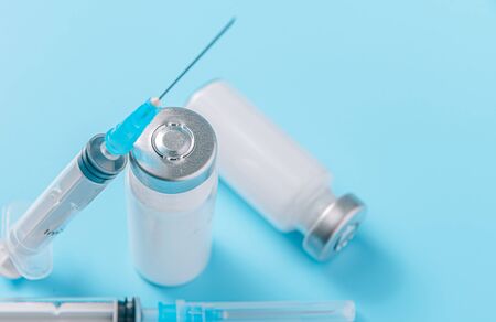 two syringes and two ampoules with medicine without a label on a blue background the concept of a coronavirus vaccineの写真素材