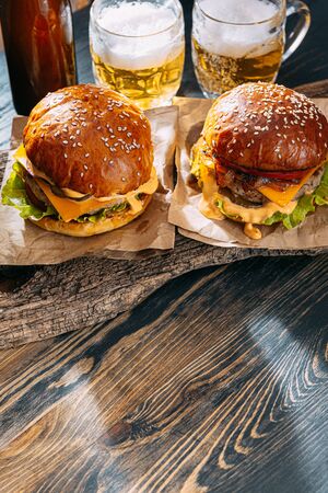 two delicious beef burger on a wooden table near two glass of cold beerの写真素材