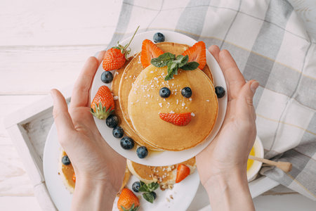 pancake breakfast for children with berries and honey in the shape of a smiling faceの写真素材