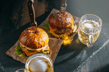 two delicious beef burger on a wooden table near two glass of cold beer