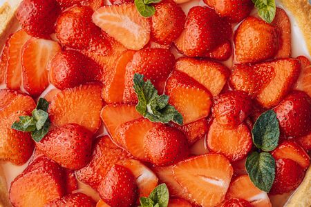 ingredients for strawberry pie, sliced strawberries are laid on top of the pie and smeared on top with lime jelly with fresh green mint leavesの写真素材