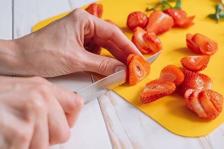 ingredients for strawberry pie, custard cake with lime zest, cutting board with sliced strawberries. female hands cut strawberries on a cutting boardの写真素材