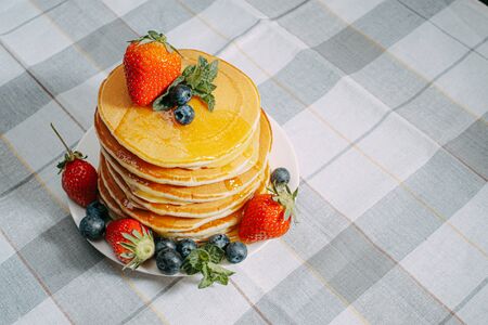 on classic homemade pancakes with berries on a white saucer on a light wooden background in a rustic styleの写真素材