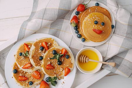 pancake breakfast for children with berries and honey in the shape of a smiling faceの写真素材