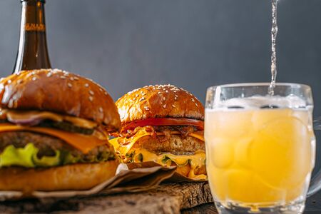 two delicious beef burger on a wooden table near two glass of cold beerの写真素材