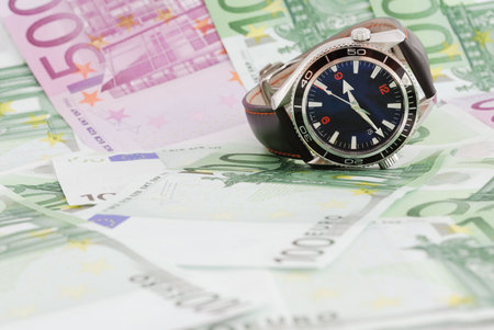 Luxury watch on background full of moneyの写真素材