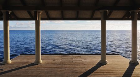 Seascape through columns on the pier. Warm sunlight.の写真素材