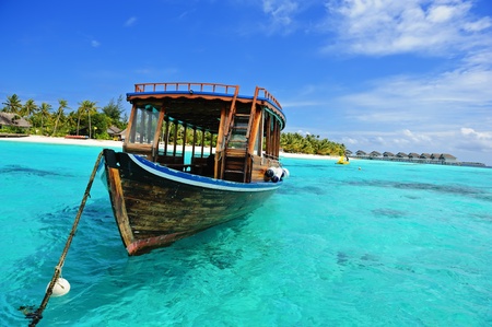 Maldivian dhoni in front of the turquoise bay and islandの写真素材
