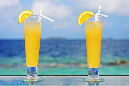 Pair of cocktails with lemon at tropical resort against blue sky and sea.の写真素材