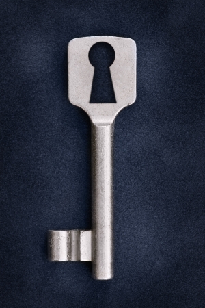Old key on a dark blue background with unusual keyholeの写真素材